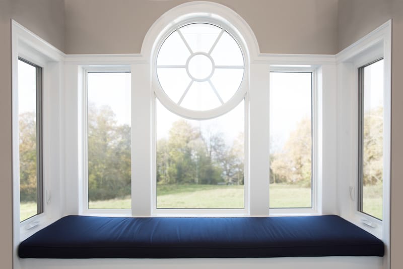 A circular architectural window above a bay window seat