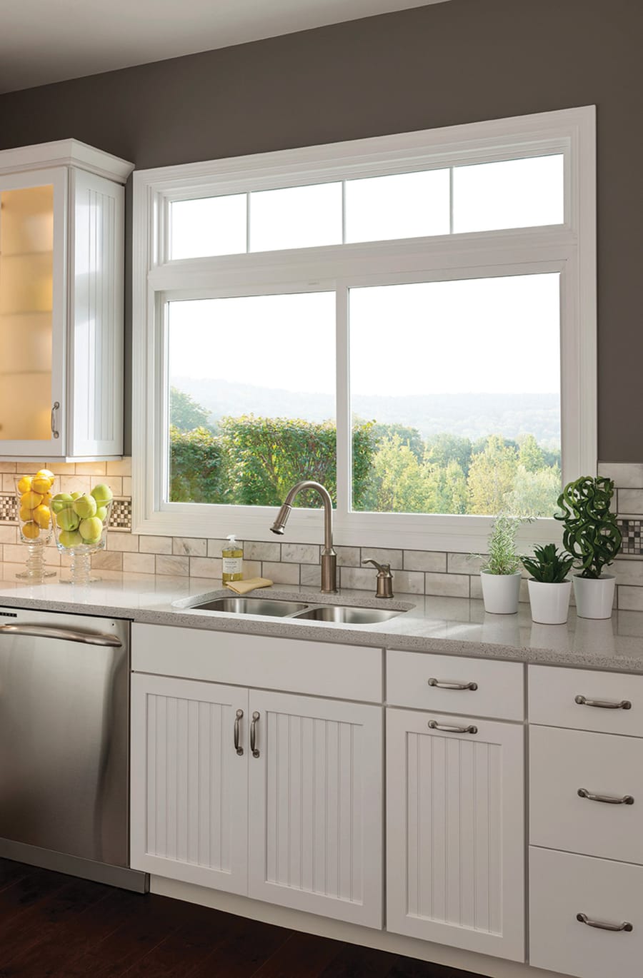 A white double slider lift out window over a kitchen sink, with a transom above